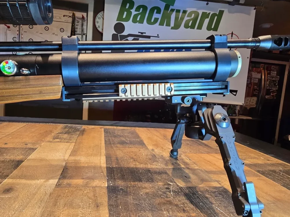 Air rifle with bipod on wooden table.