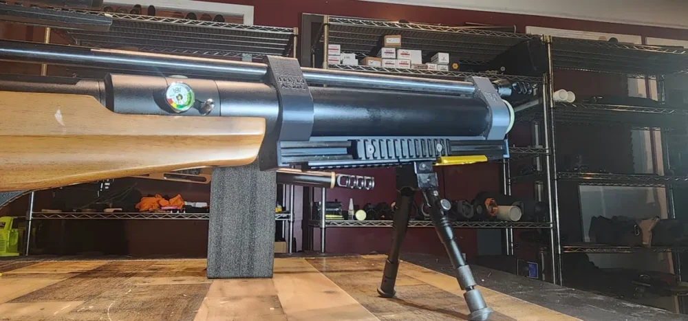 Air rifle with bipod on wooden table.